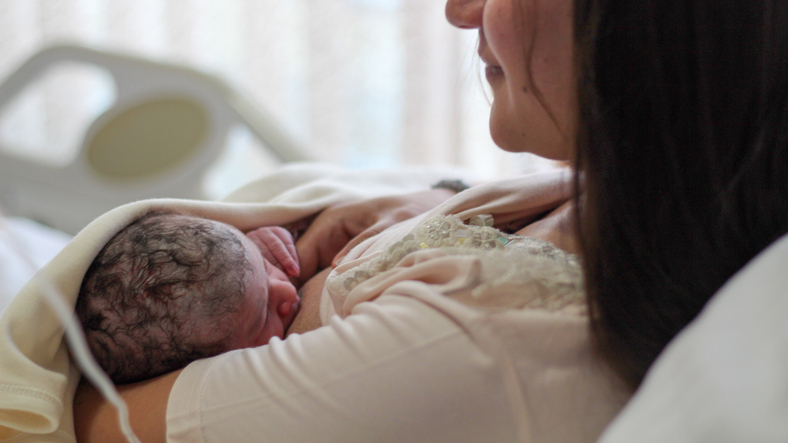 Mother very happy in hospital with new baby and she is breastfeeding her baby