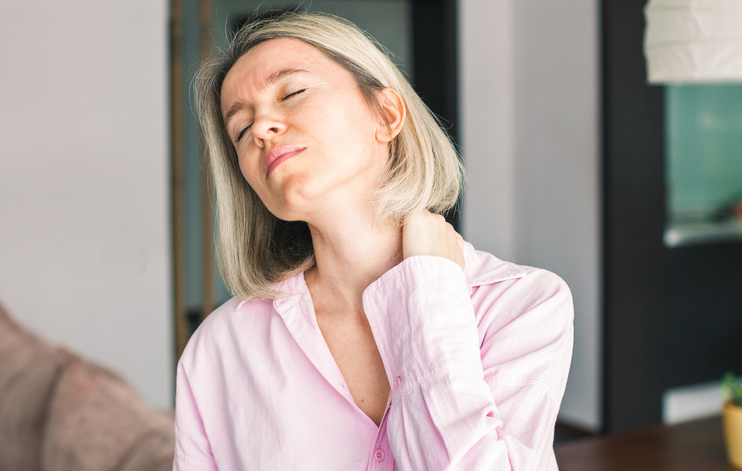 Tired stressed middle aged businesswoman suffering from neck pain working from home office. Overworked adult lady messaging neck feeling hurt pain from incorrect posture