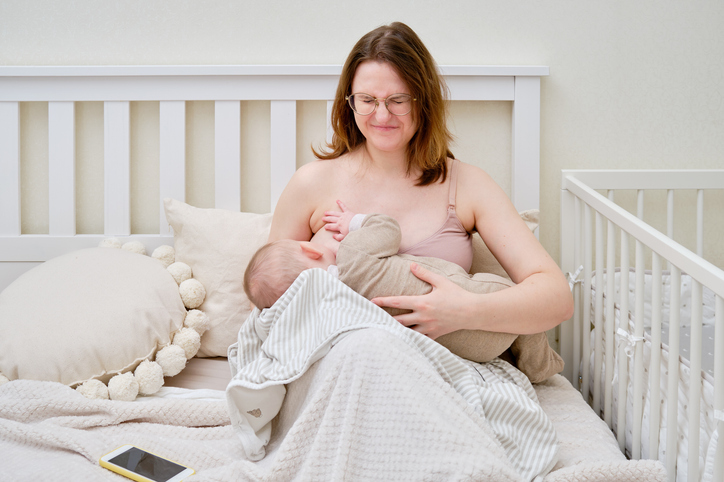 Pain and problems in a woman while breastfeeding a baby. Mother experiences discomfort while breastfeeding