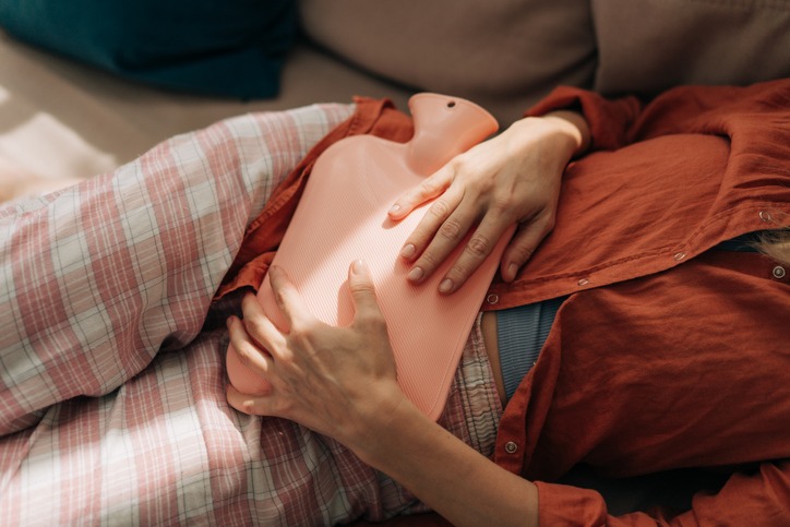 Sick woman with a hot water bottle on her stomach.